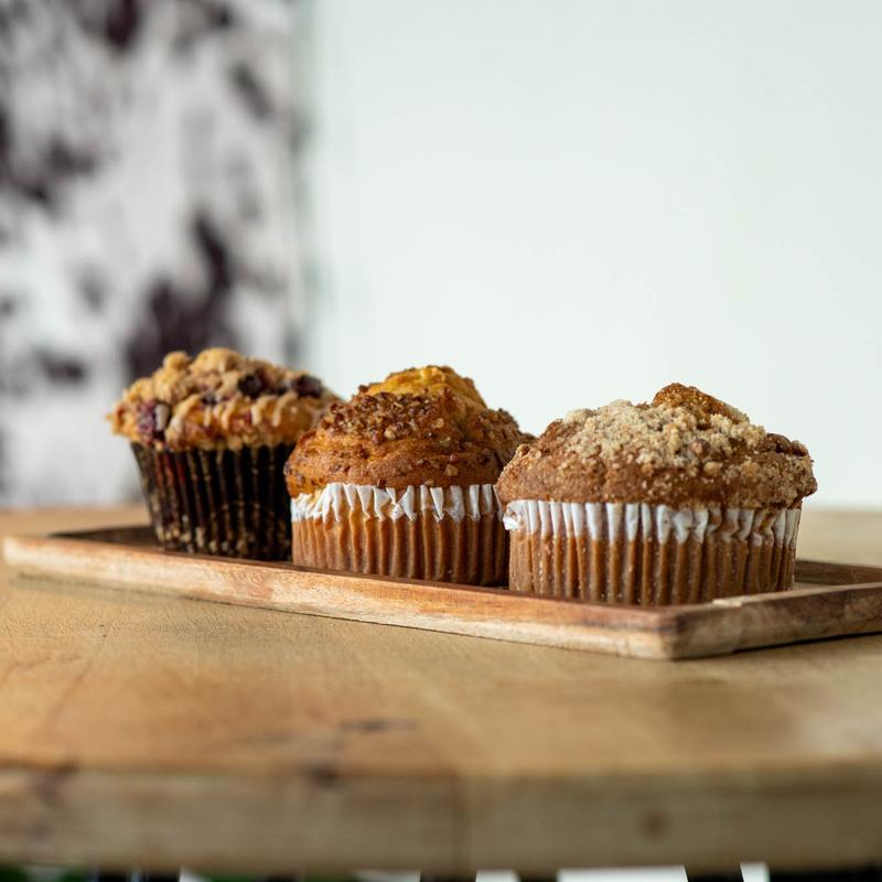 A rustic table set with various traditional pastries and a small bottle, surrounded by green foliage.