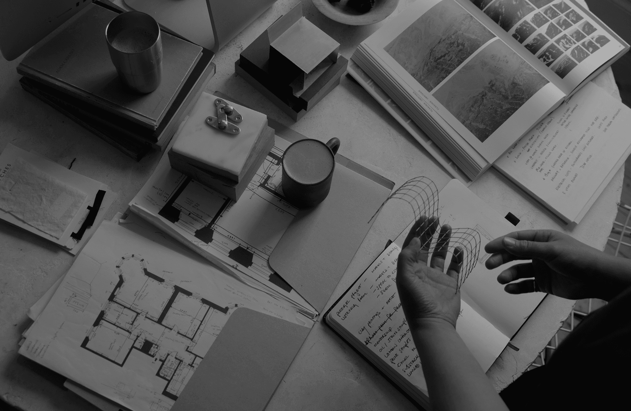 Black and white image of people working at a table with laptops, showing hands gesturing during discussion of digital content displayed on screens, with fabrica® logo in the corner.