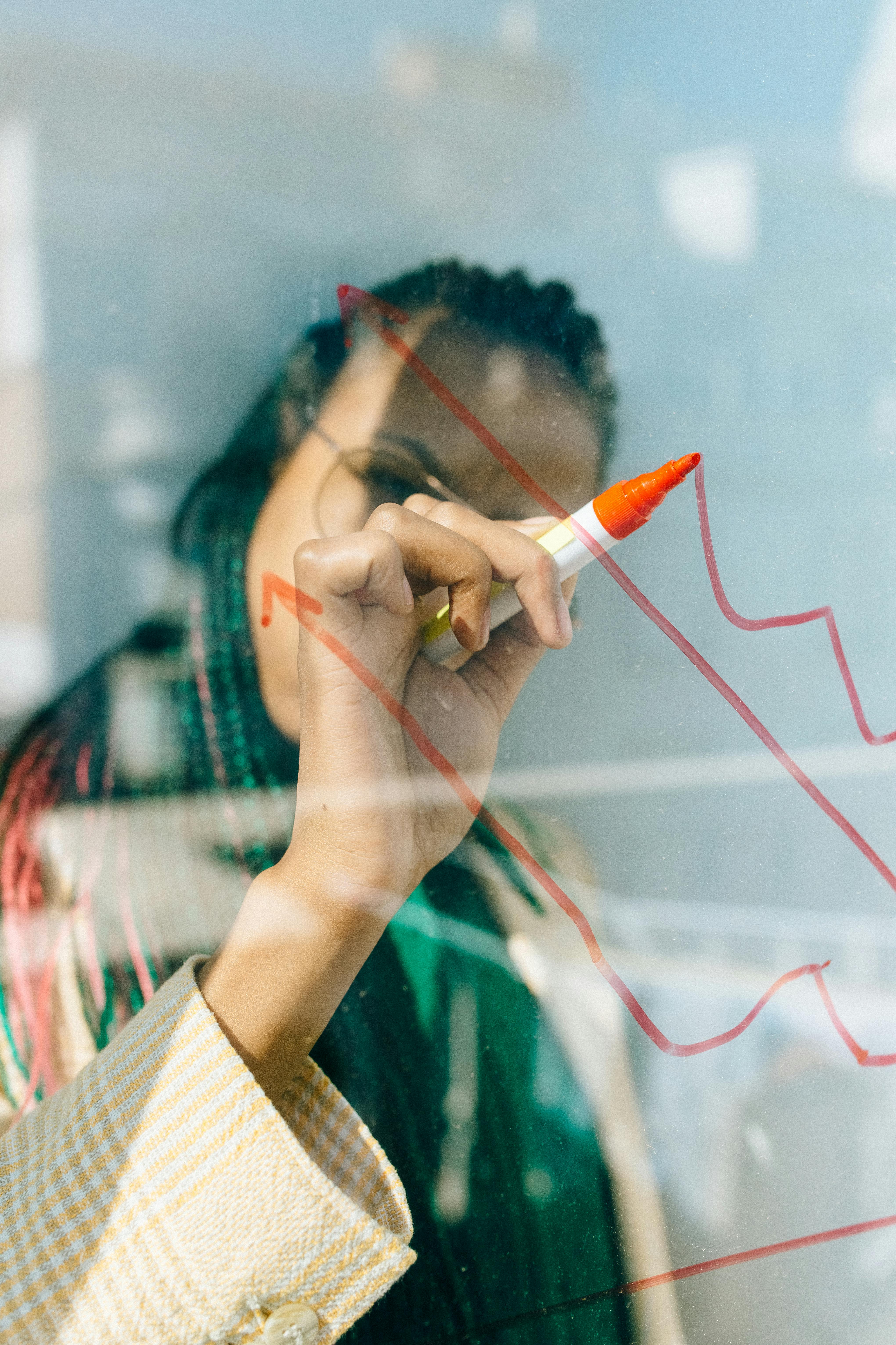 Person drawing a graph on a glass board