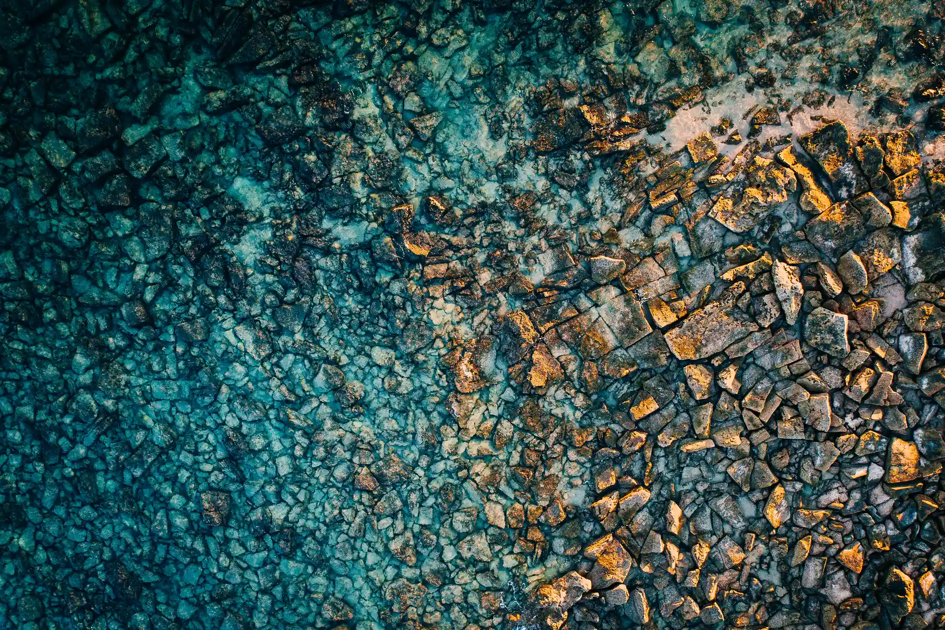 Aerial looking down on a rocky reef platform under shallow green water