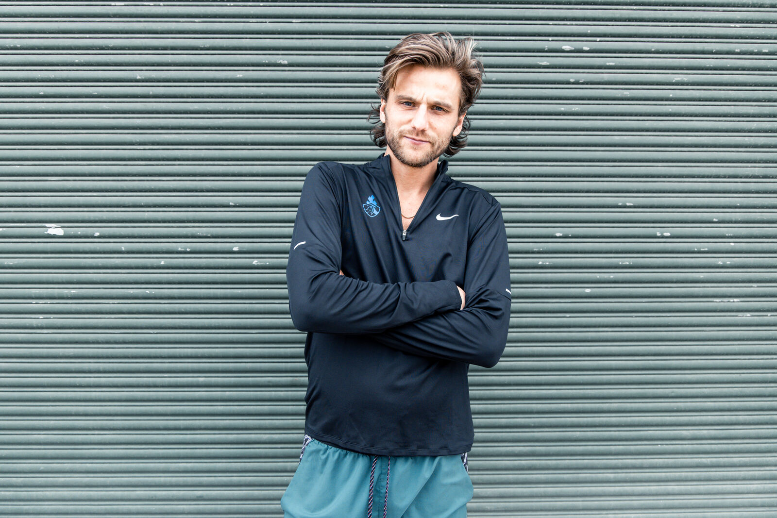 Nike shoot, an athlete with arms crossed in front of a green shutter