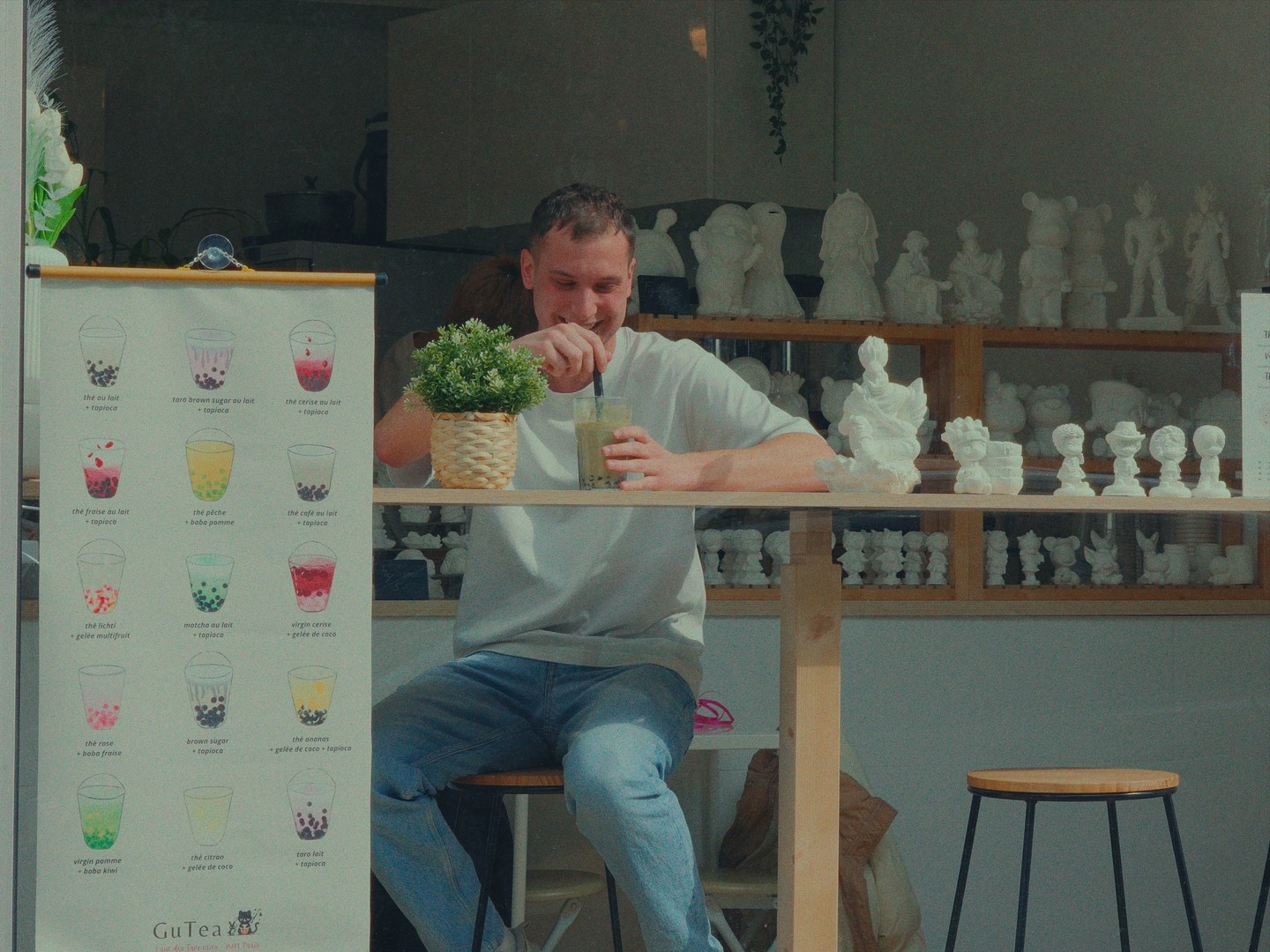 Scène détendue chez GuTea, un client profite de son bubble tea dans un cadre artistique.