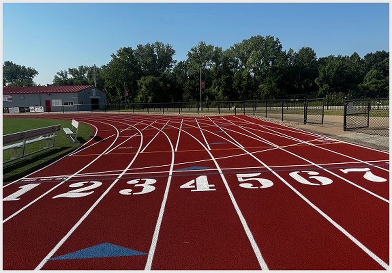 Red running track with fresh lane numbers and clear white striping at a school facility.
