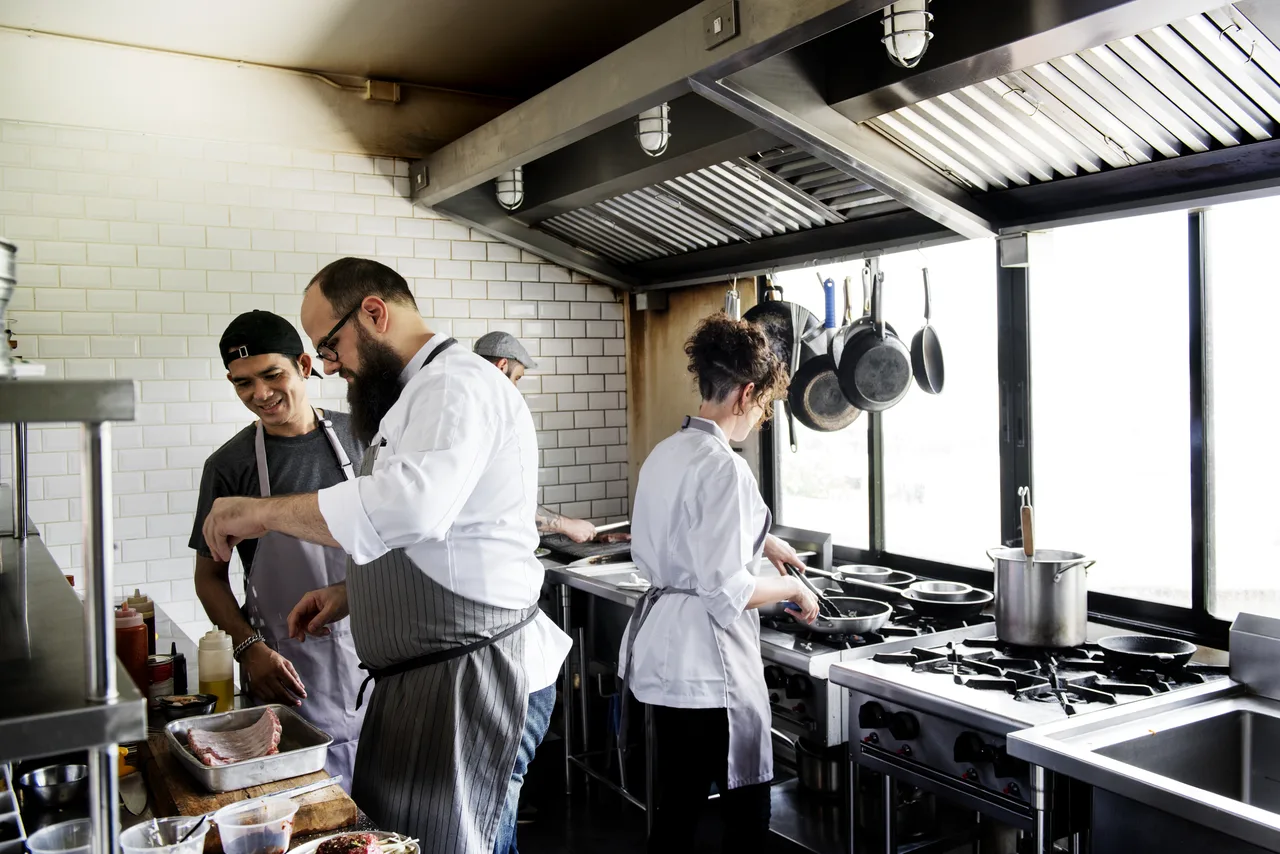 Bir restoran mutfağında ocak başında birlikte yemek hazırlayan aşçı ekibi