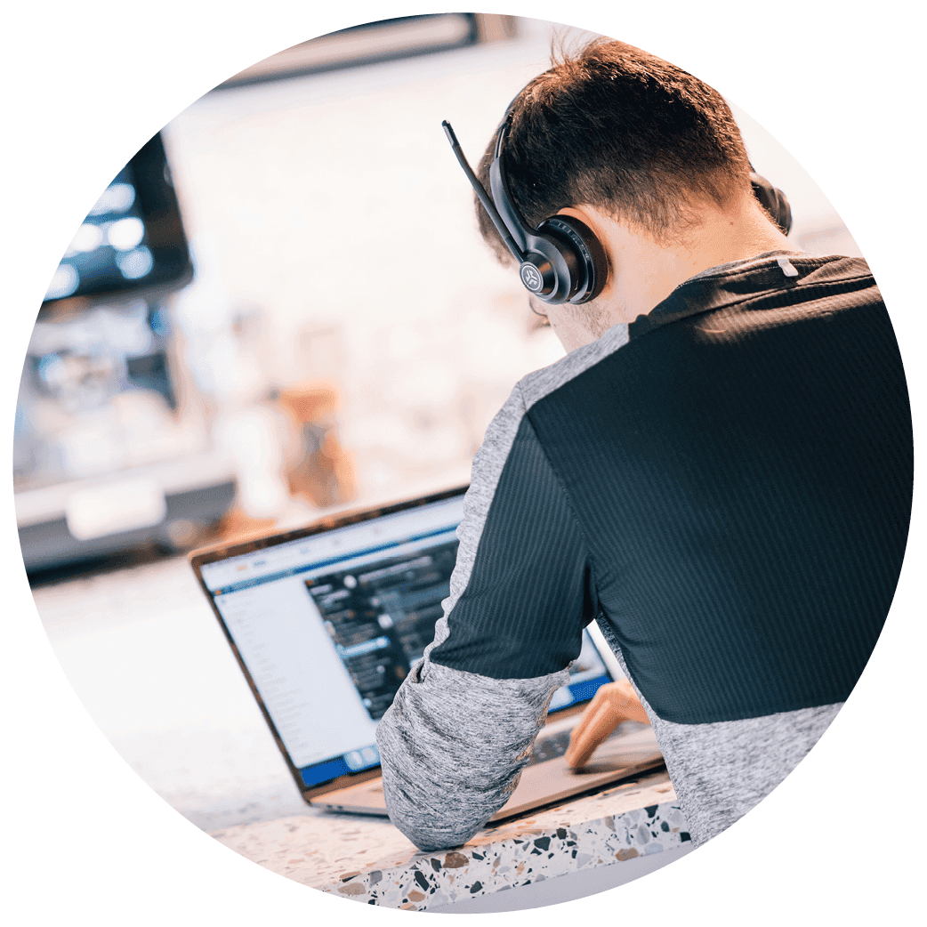 Person wearing a headset and using a laptop while seated at a counter.