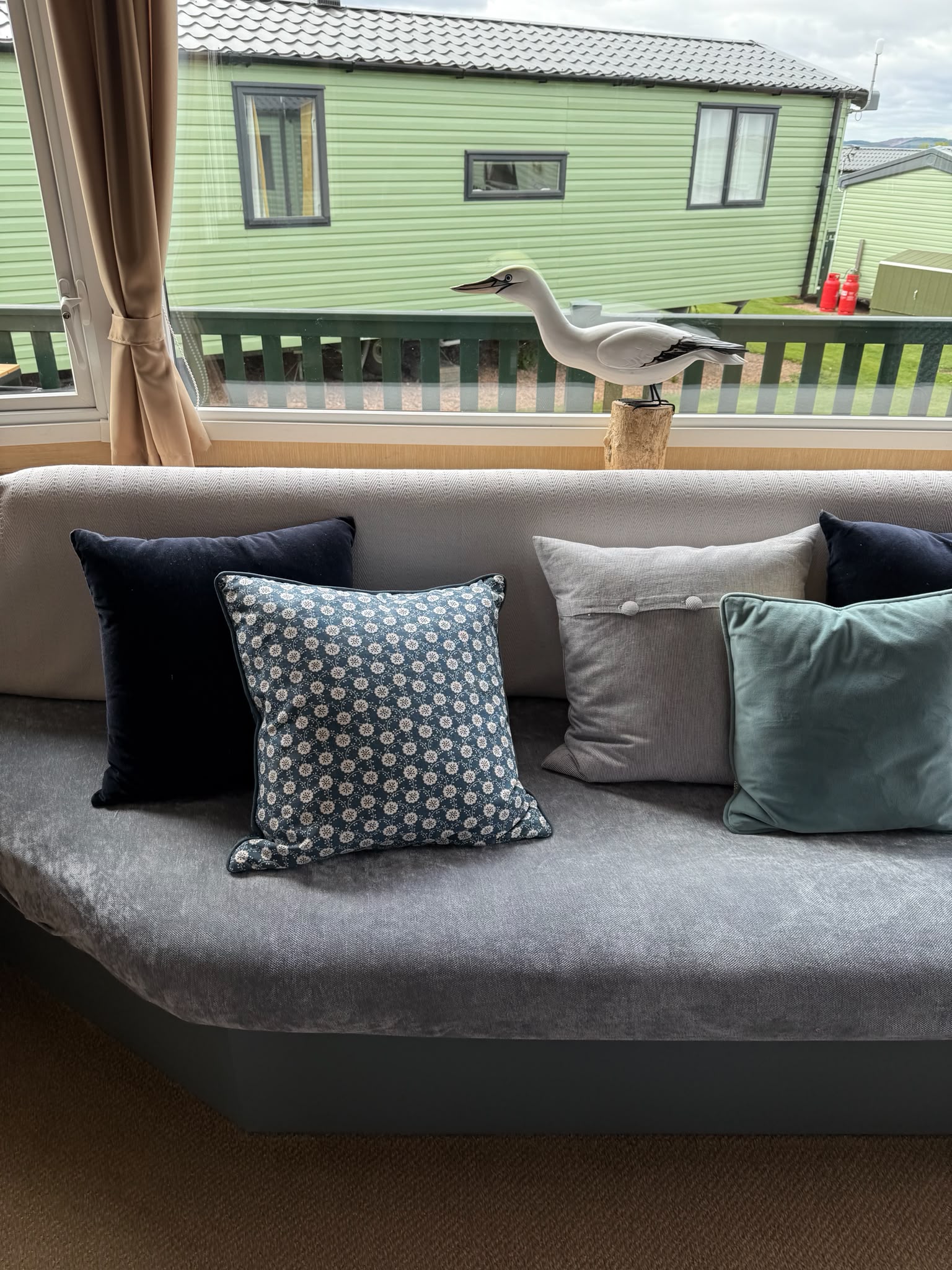 Corner couch with a bird ornament sitting on the widnow sill