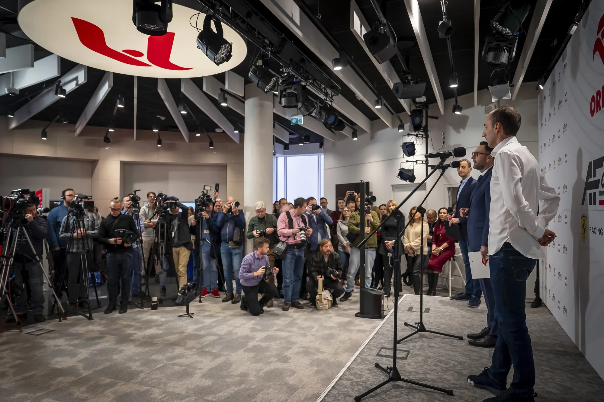 Robert Kubica podczas konferencji prasowej ORLEN – dziennikarze nagrywają wystąpienie.