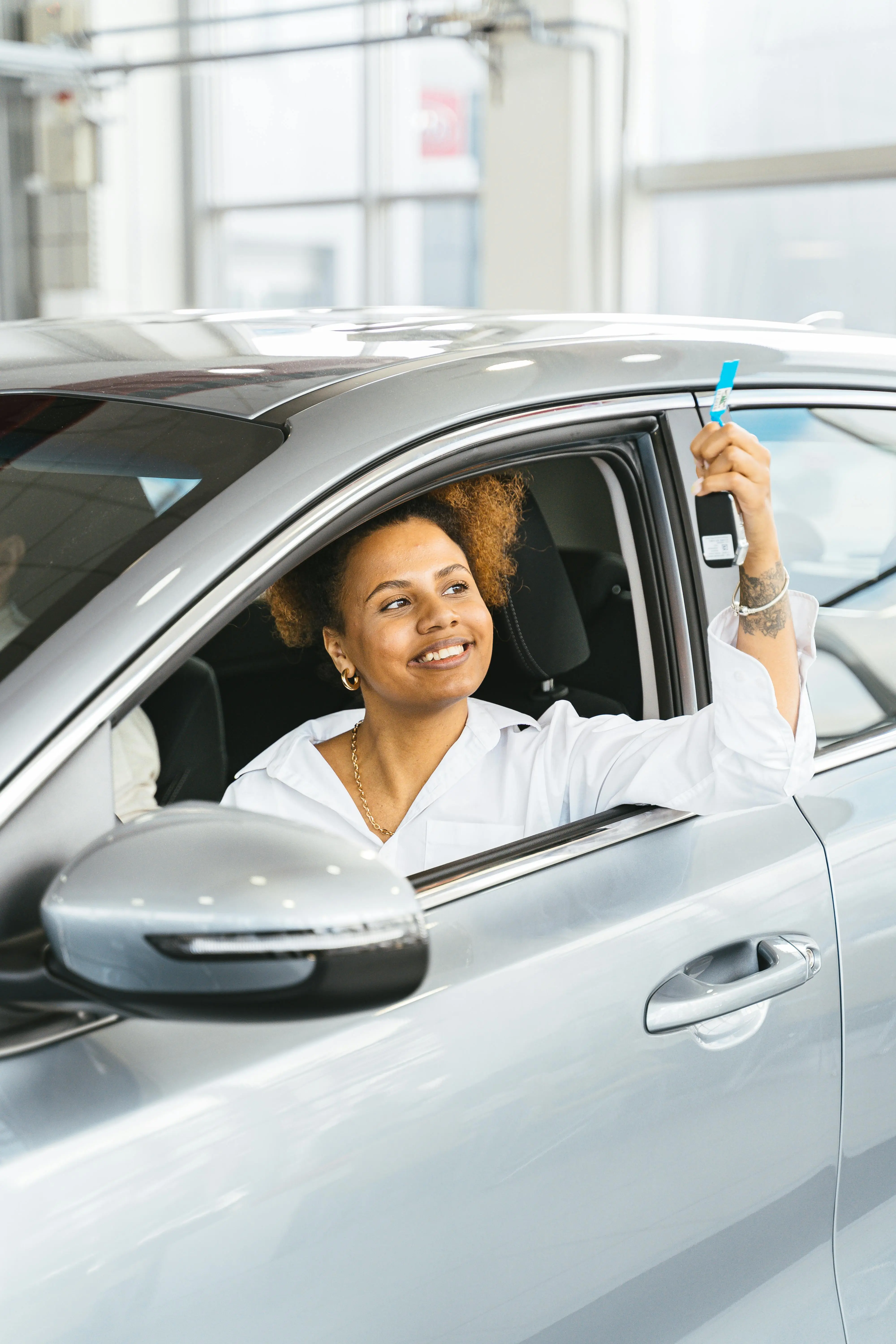 Femme fière brandissant les clés de sa voiture neuve.