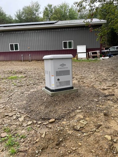 Briggs & Stratton standby generator installed outside a metal-sided building on a gravel pad.