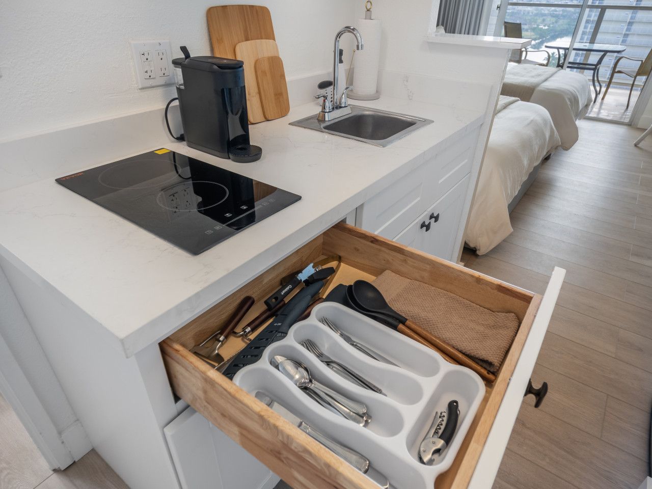 Kitchenette utensil drawer beside the induction cooktop and sink