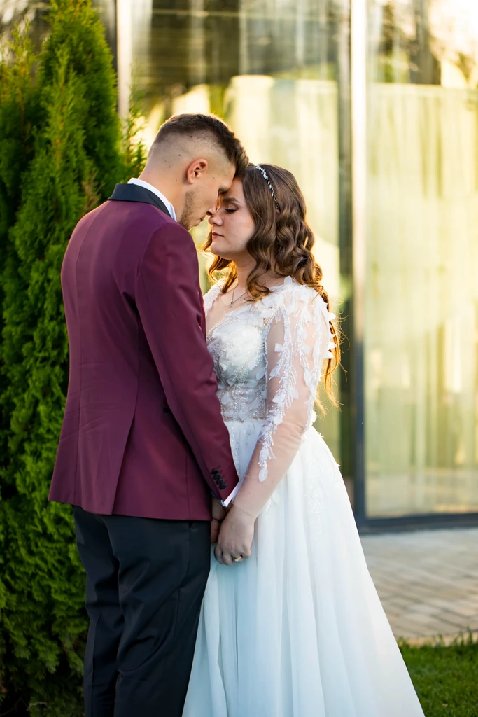 A bride in a lace wedding dress gently holds.