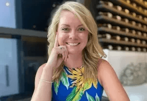 Professional photo of Jackie Tomes, woman with blonde hair wearing a patterned yellow top, smiling at camera