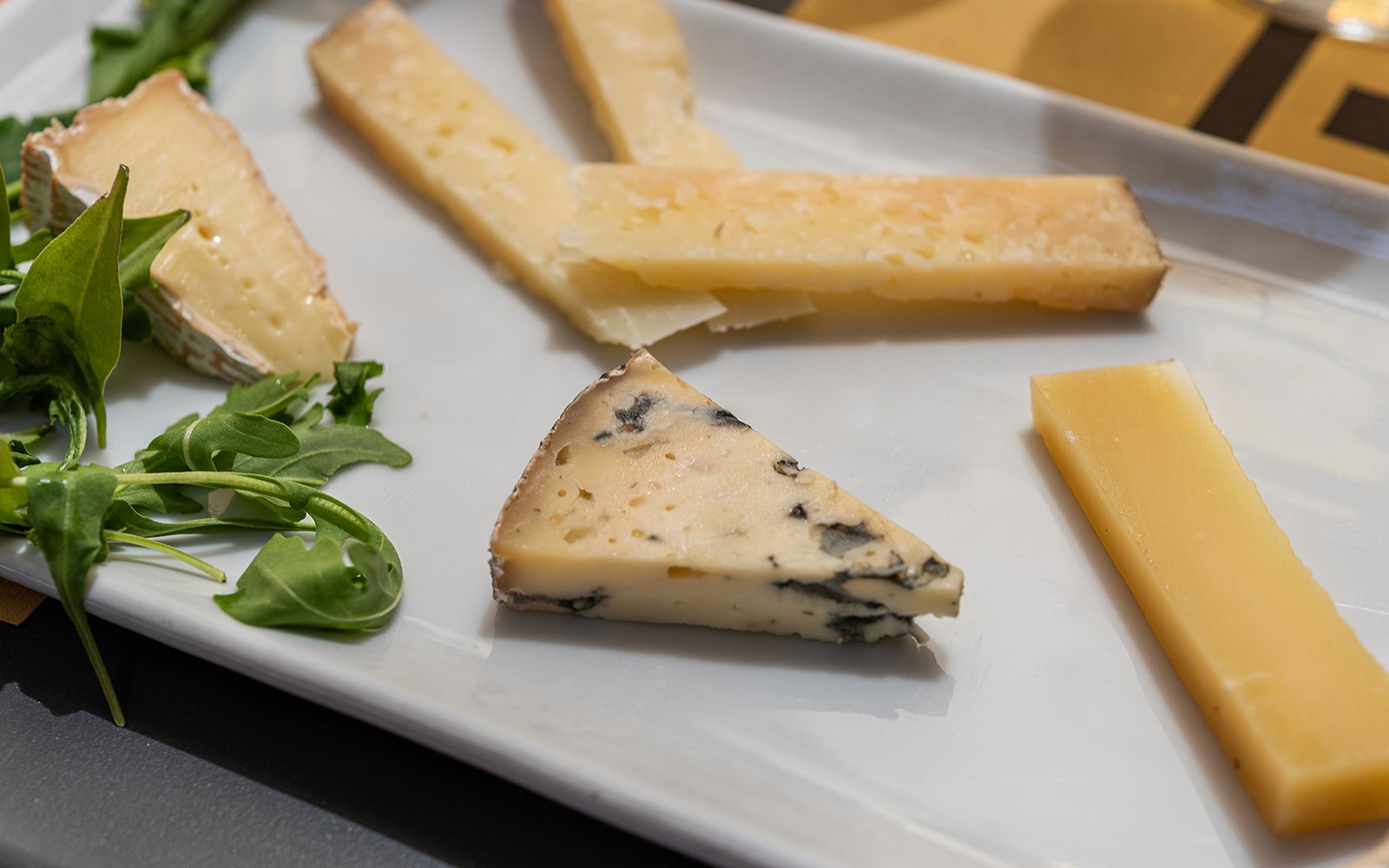 Assorted cheeses with arugula on a plate during a guided food and wine tour in Rome.