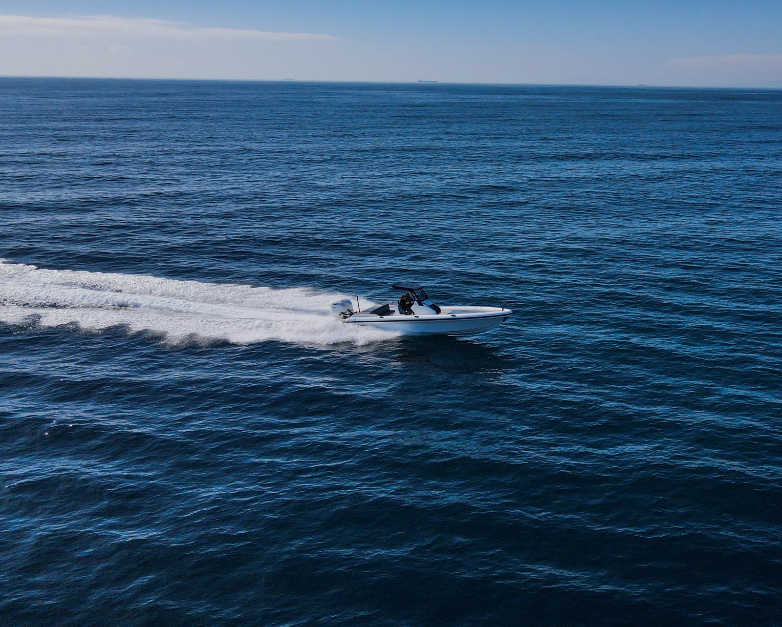 White Rock 36 speedboat with captain at helm cruising calm blue waters near Paros coastline with hills in background.