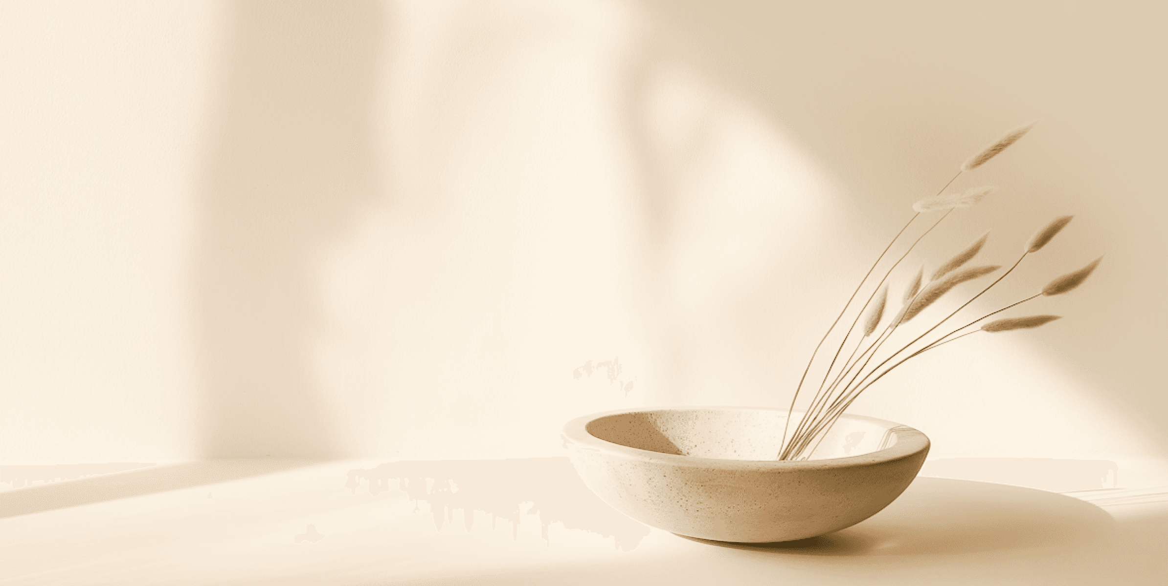 Minimalist beige bowl with dried grass stems in soft natural light.