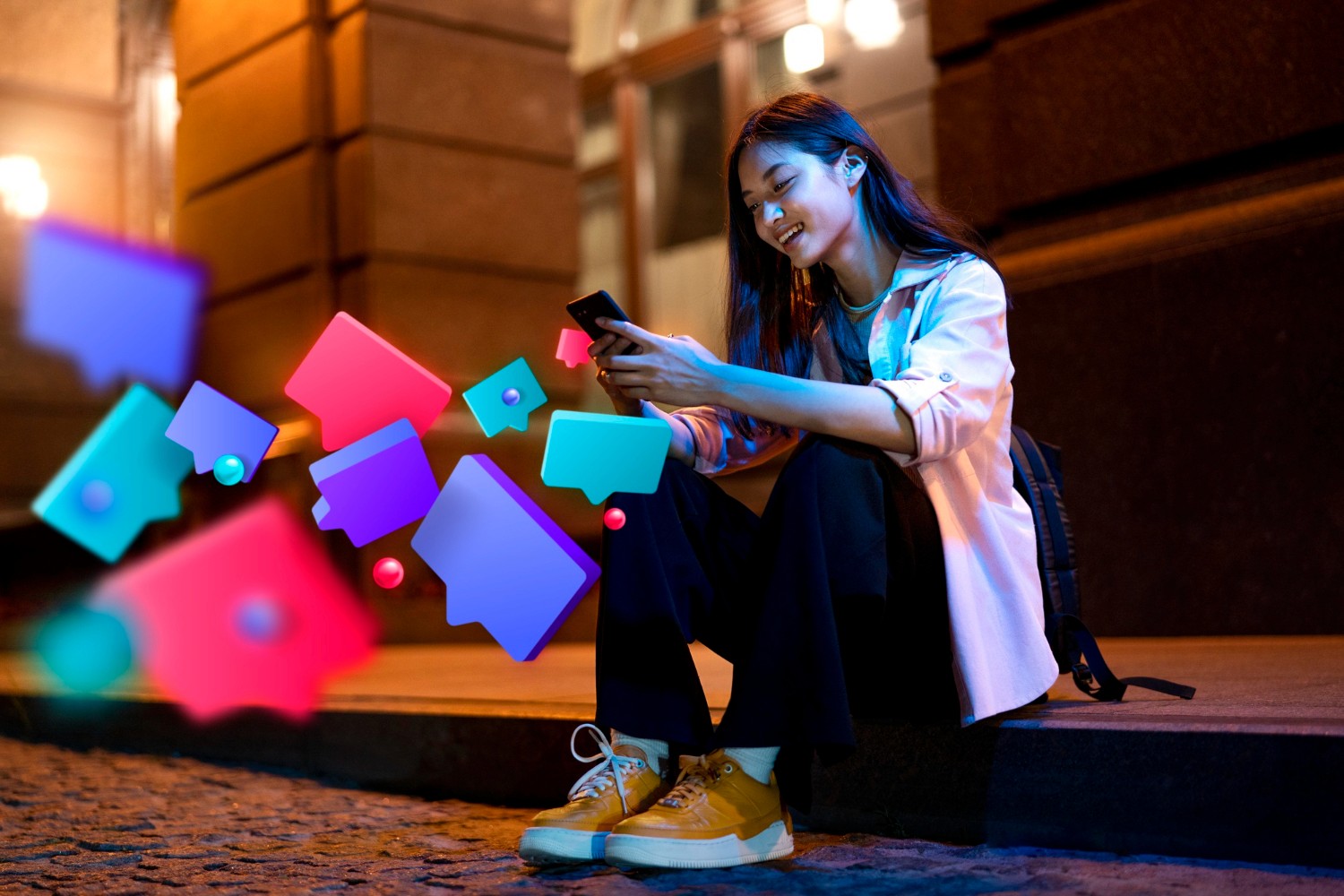 A woman seated on the ground, holding a phone, surrounded by a vibrant, colorful object nearby.