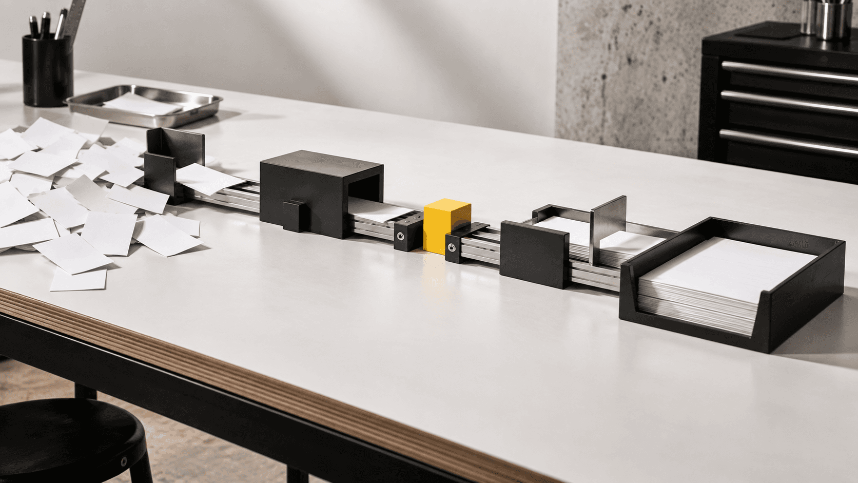 An industrial workbench illustration turns scattered paper into an organised sequence, with a yellow review checkpoint.