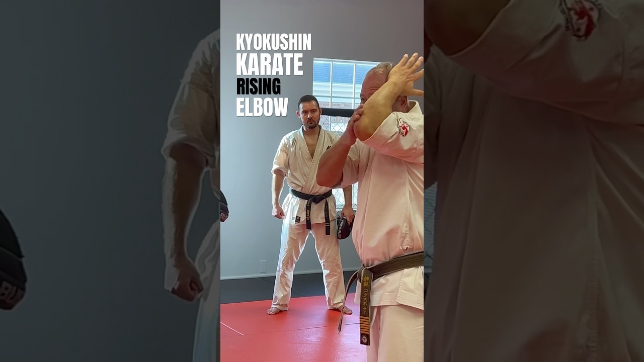 Two Kyokushin karateka demonstrating a rising elbow on the dojo mat.