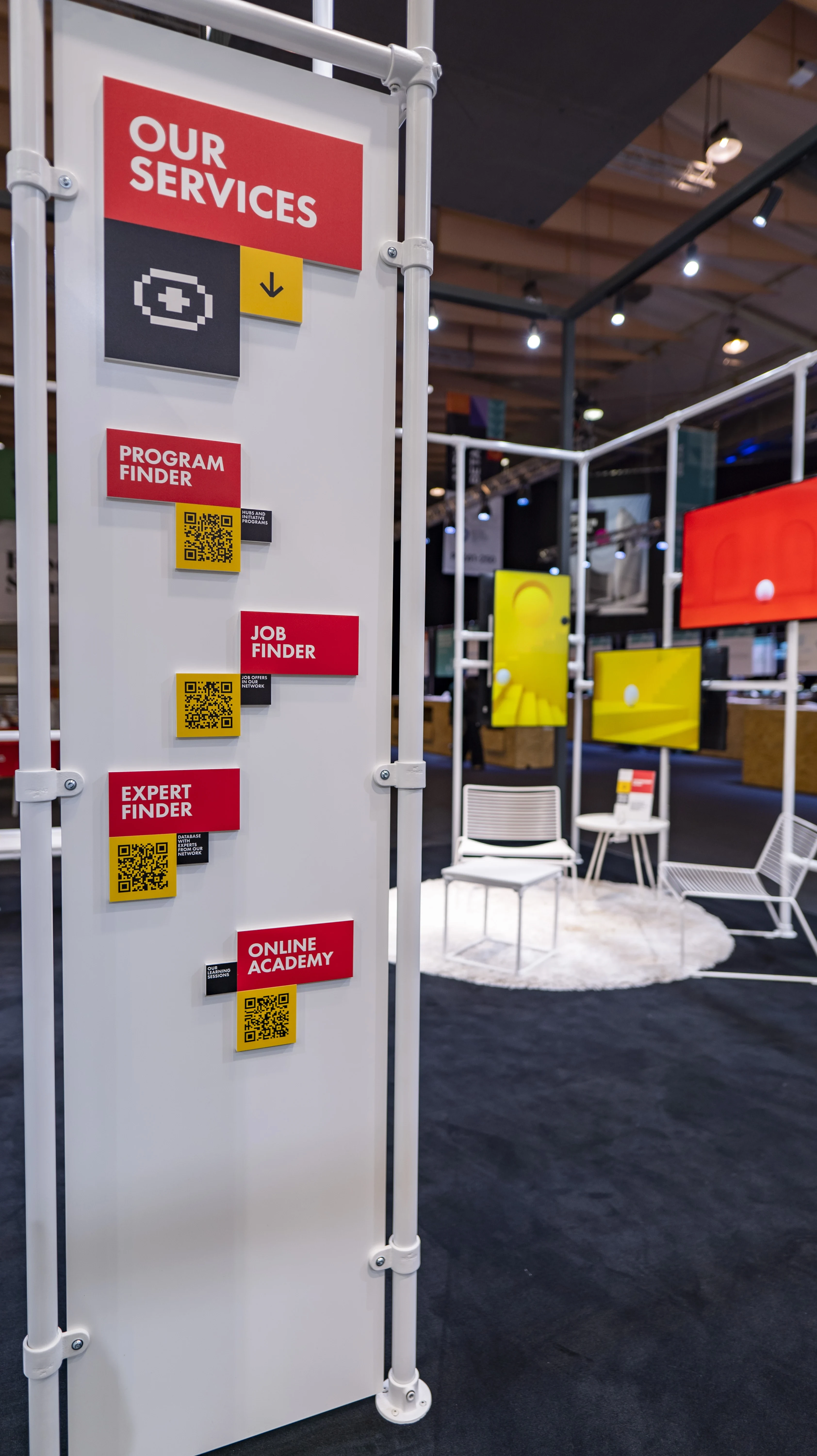 Service signage pillar with red labels and QR codes at the German Pavilion booth at Web Summit.