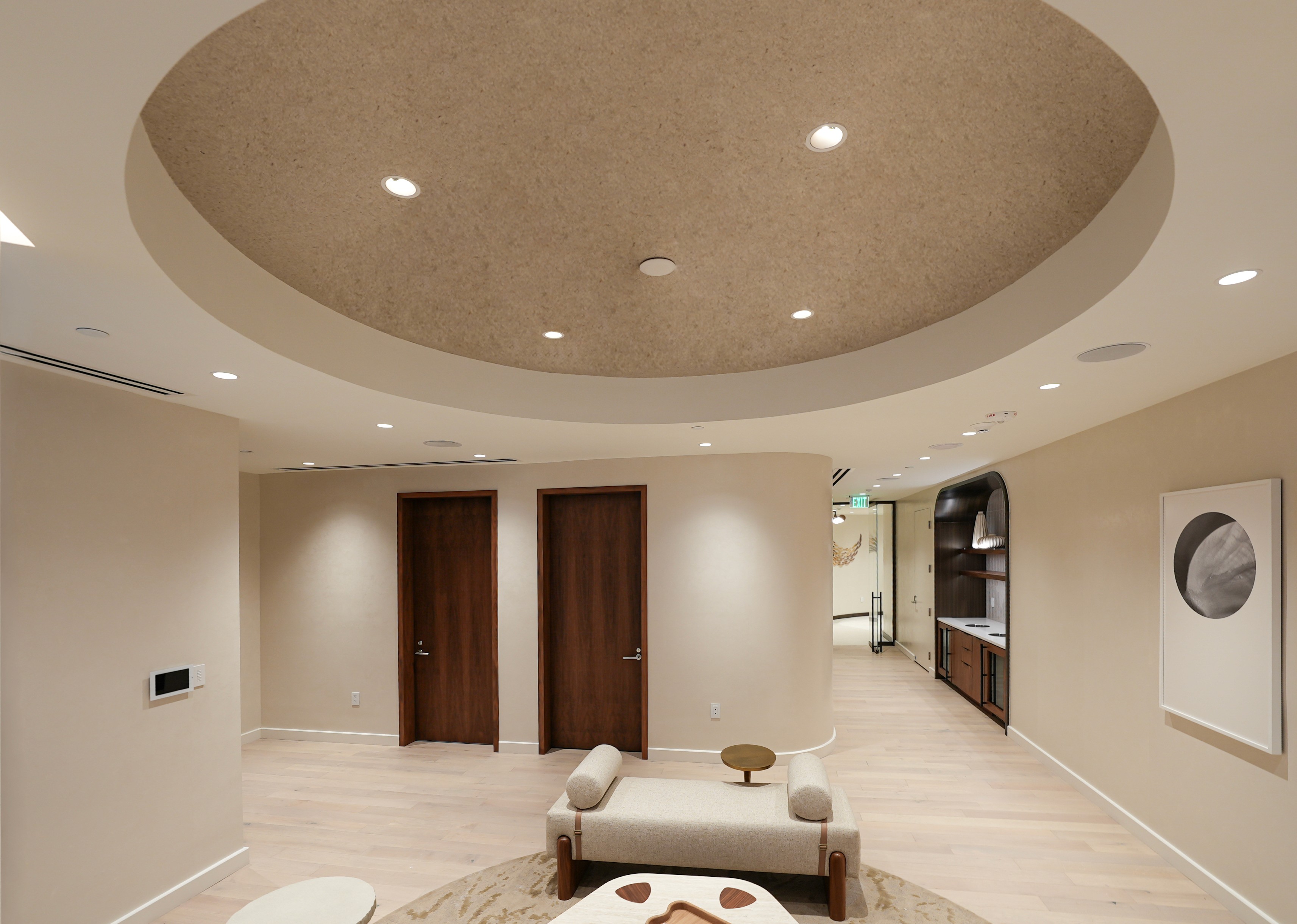 A modern bedroom featuring wooden accents, decorative wall plates, and a doorway leading to a bright hallway.