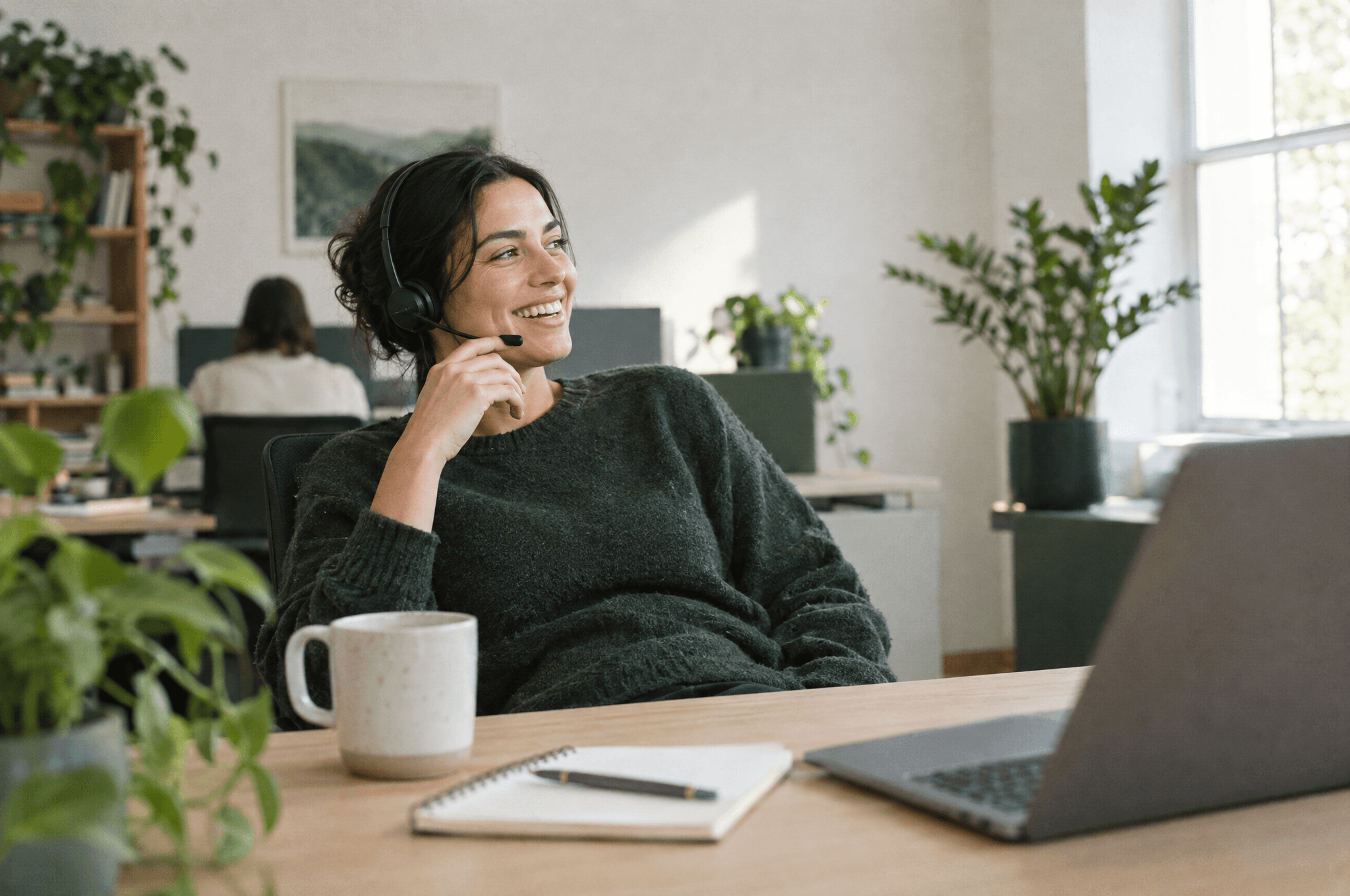 Support specialist with a headset smiling during a call at her desk