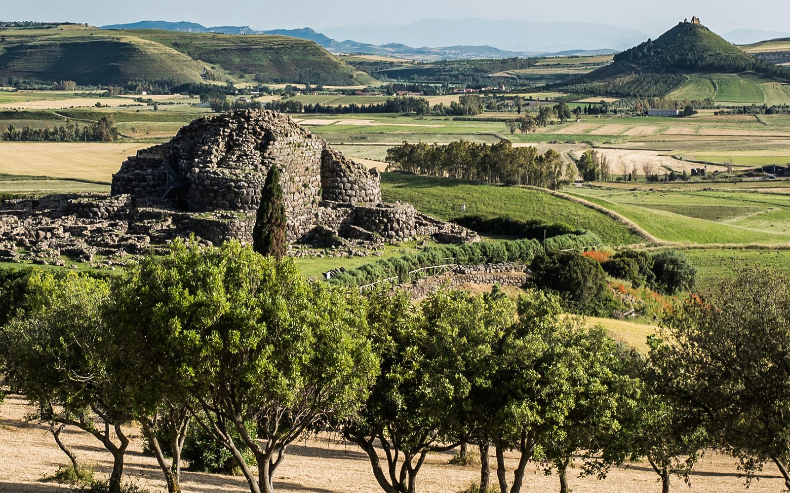 Ancient stone structure at Barumini UNESCO Site with Giara di Gesturi Plateau in the background.