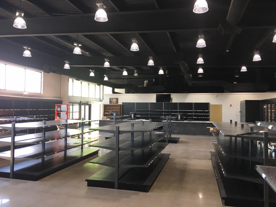 Interior of a spacious retail space with shelves and bright overhead lights, awaiting products.