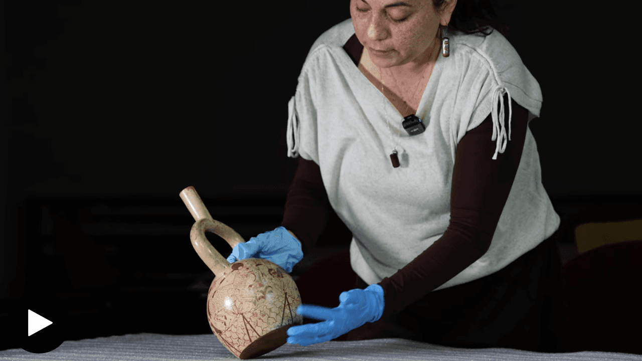 Solsiré Cusicanqui handling a stirrup-spout Moche vessel.