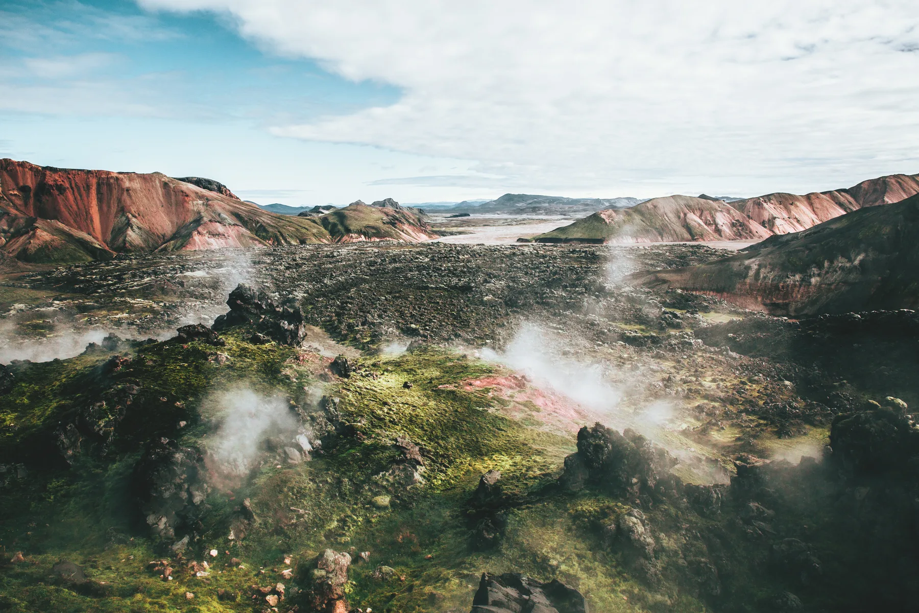Steam rising from a geothermal field among moss and coloured rhyolite hills