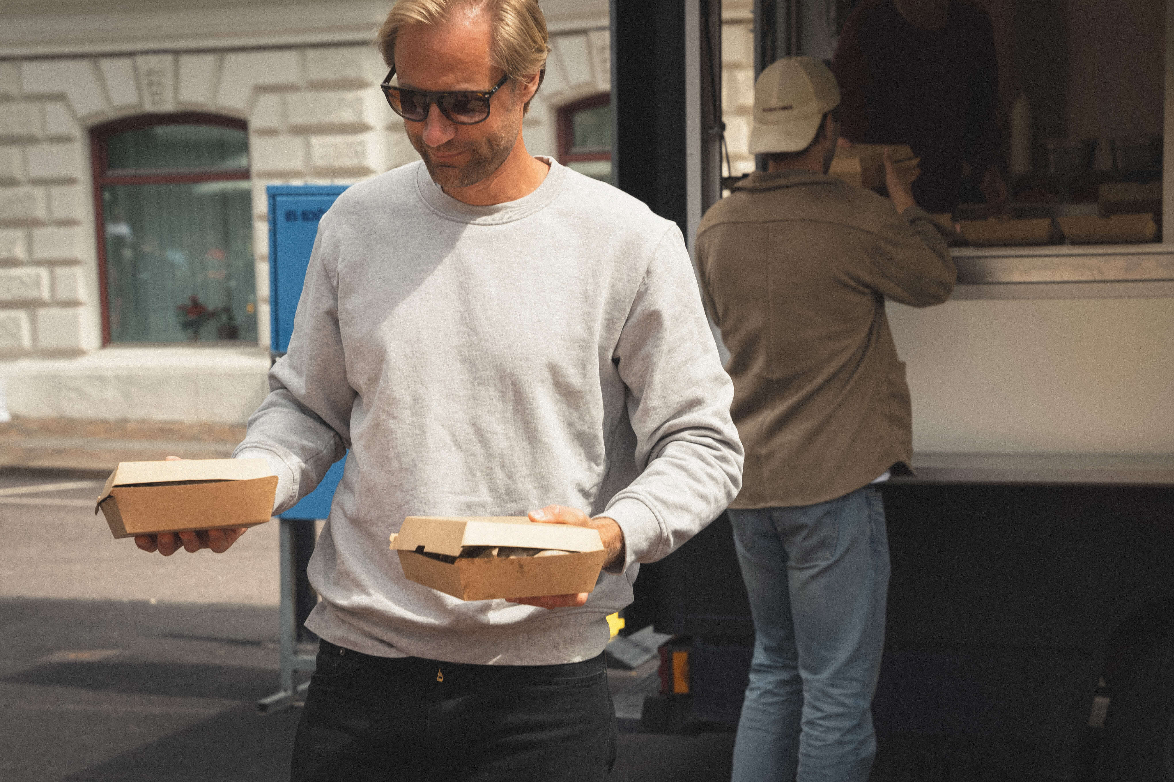 Kund hämtar mat från Oss bröd emellan foodtruck vid ett event