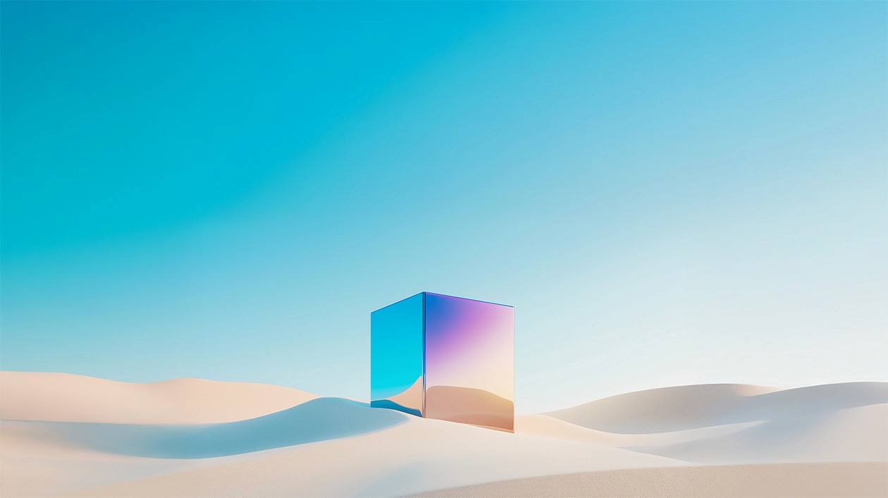 A surreal landscape featuring a large, reflective cube situated in a desert with smooth, undulating sand dunes. The cube has iridescent surfaces that reflect the colors of the sky, blending shades of blue, pink, and purple. The sky above is clear with a gradient from deep blue at the top to a lighter blue near the horizon, creating a striking contrast with the sandy environment.