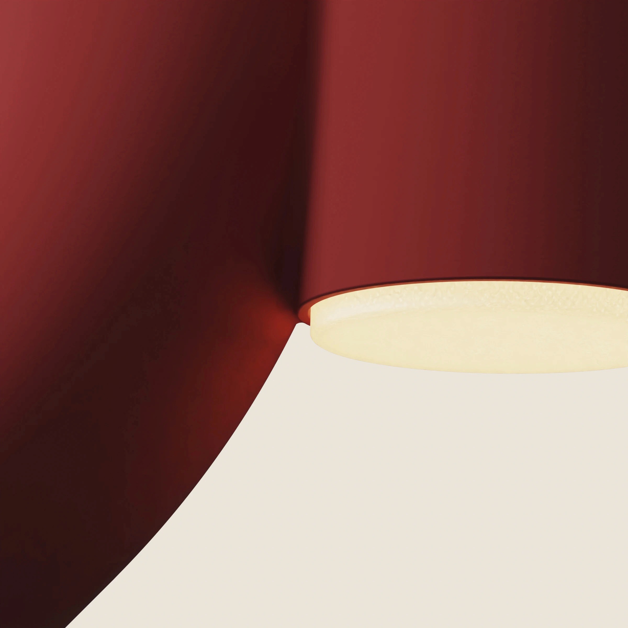 Close-up of a red lamp's bend meeting a glowing cream disc at the end of the tube