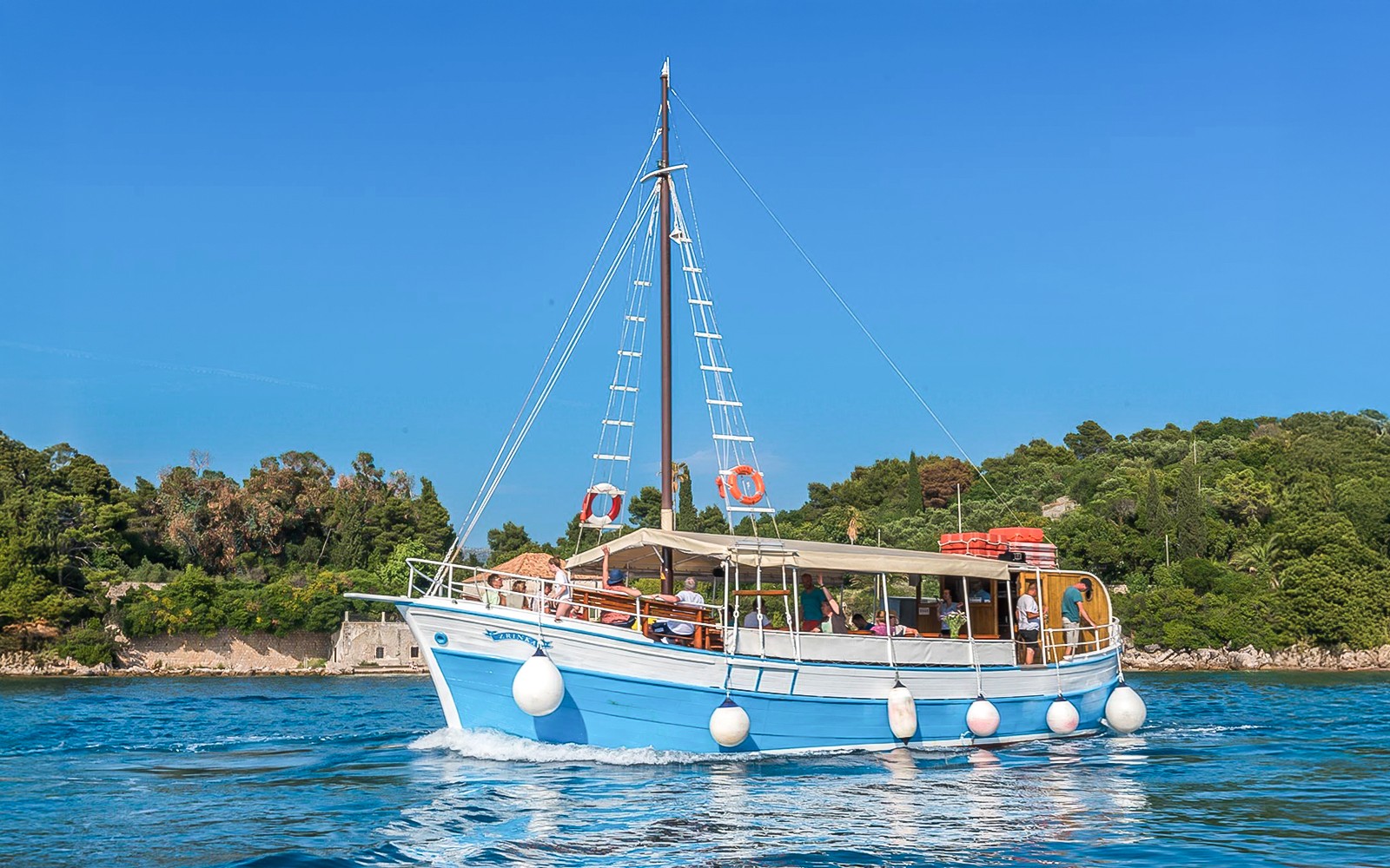 Boat cruising near Elaphiti Islands with passengers enjoying the view.
