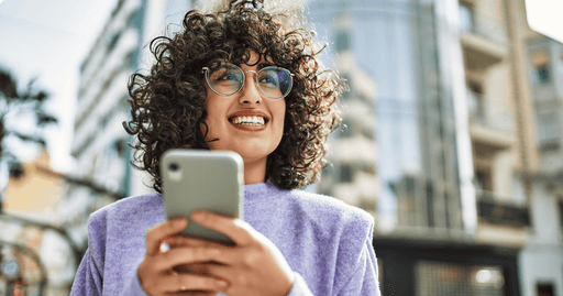 Happy employee using smartphone for team wellbeing challenge, smiling whilst engaging with workplace wellness programme