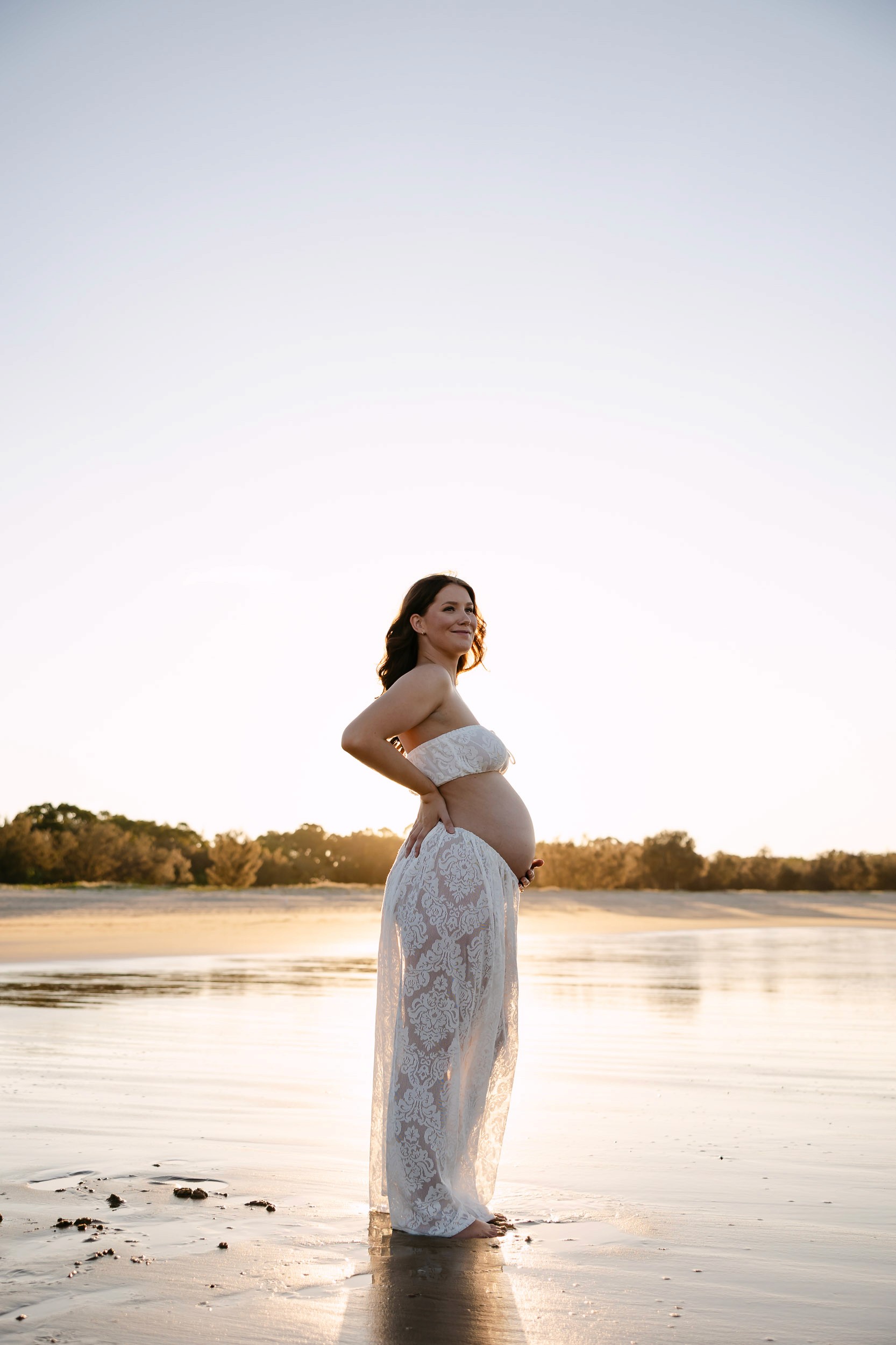 Pregnant woman with setting sun behind her on the beach