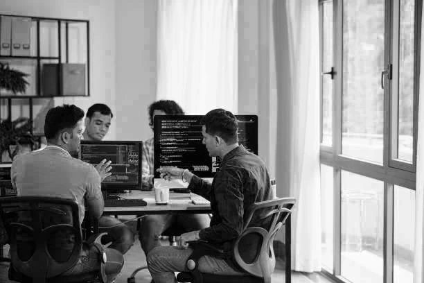software developers seated discussing a project with laptops open