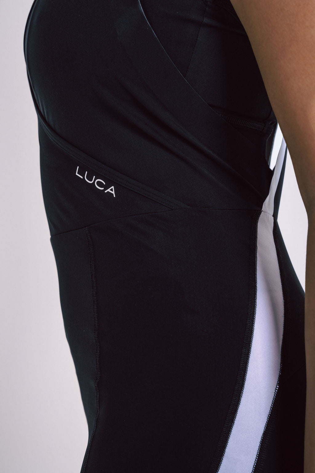 Close-up-side-view-of-a-black- athletic-race-suit-showing-the-LUCA-logo-and-a-vertical-white- contrast-panel