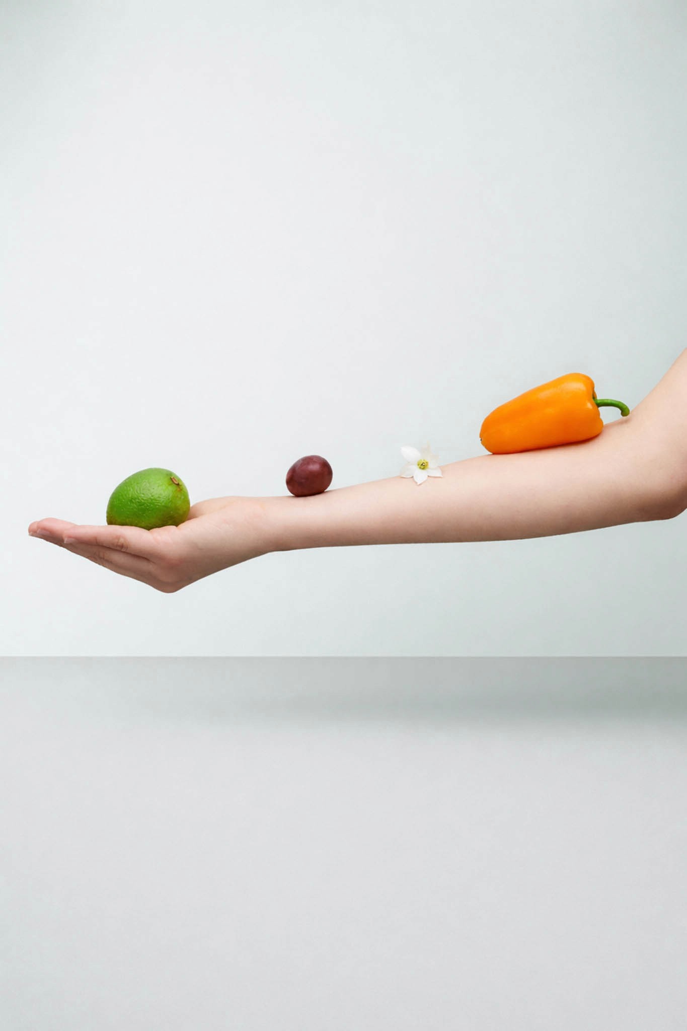 photo de bras avec des fruits, des légumes et une fleur posés dessus