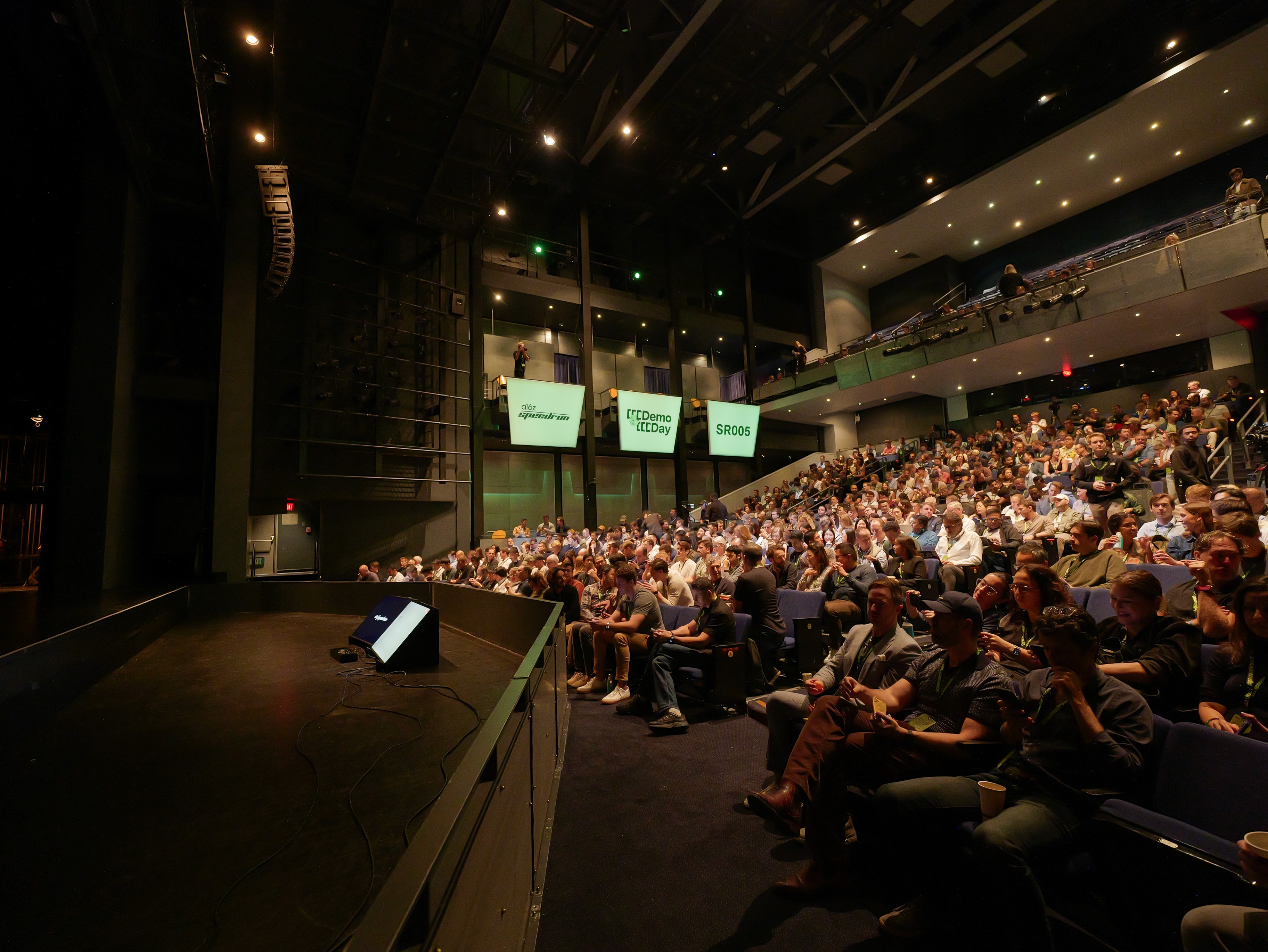 Dex on stage at a16z Speedrun Demo Day SR005 facing a large seated audience