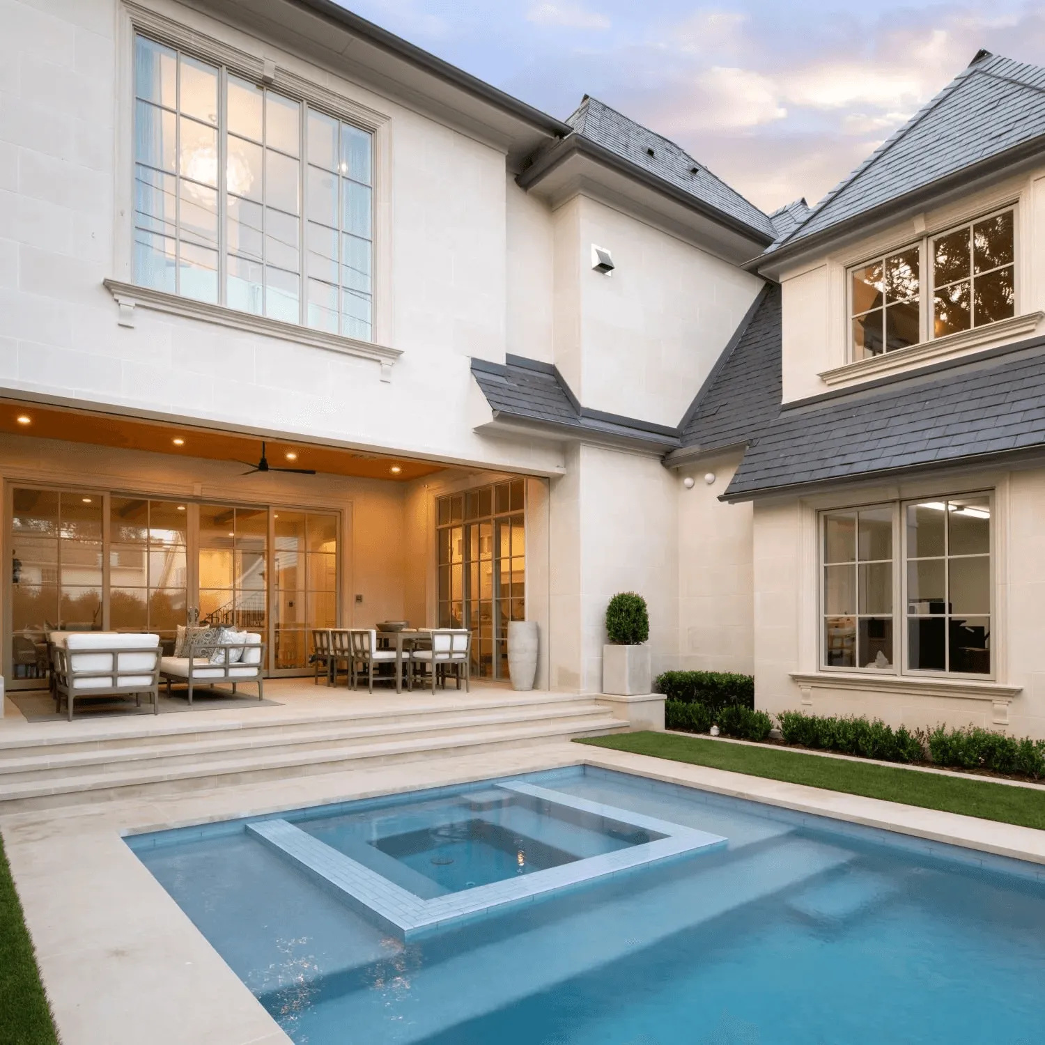 Symmetrical front yard landscape design with geometric walkway and matching planters at French country home in Park Cities Dallas