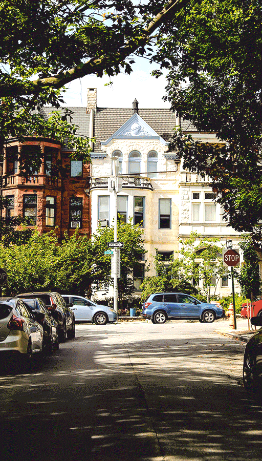 Plate with a seared salmon fillet topped with green herb garnish and sauce, served on a white dish placed on a dark green marble table beside a white candlestick.