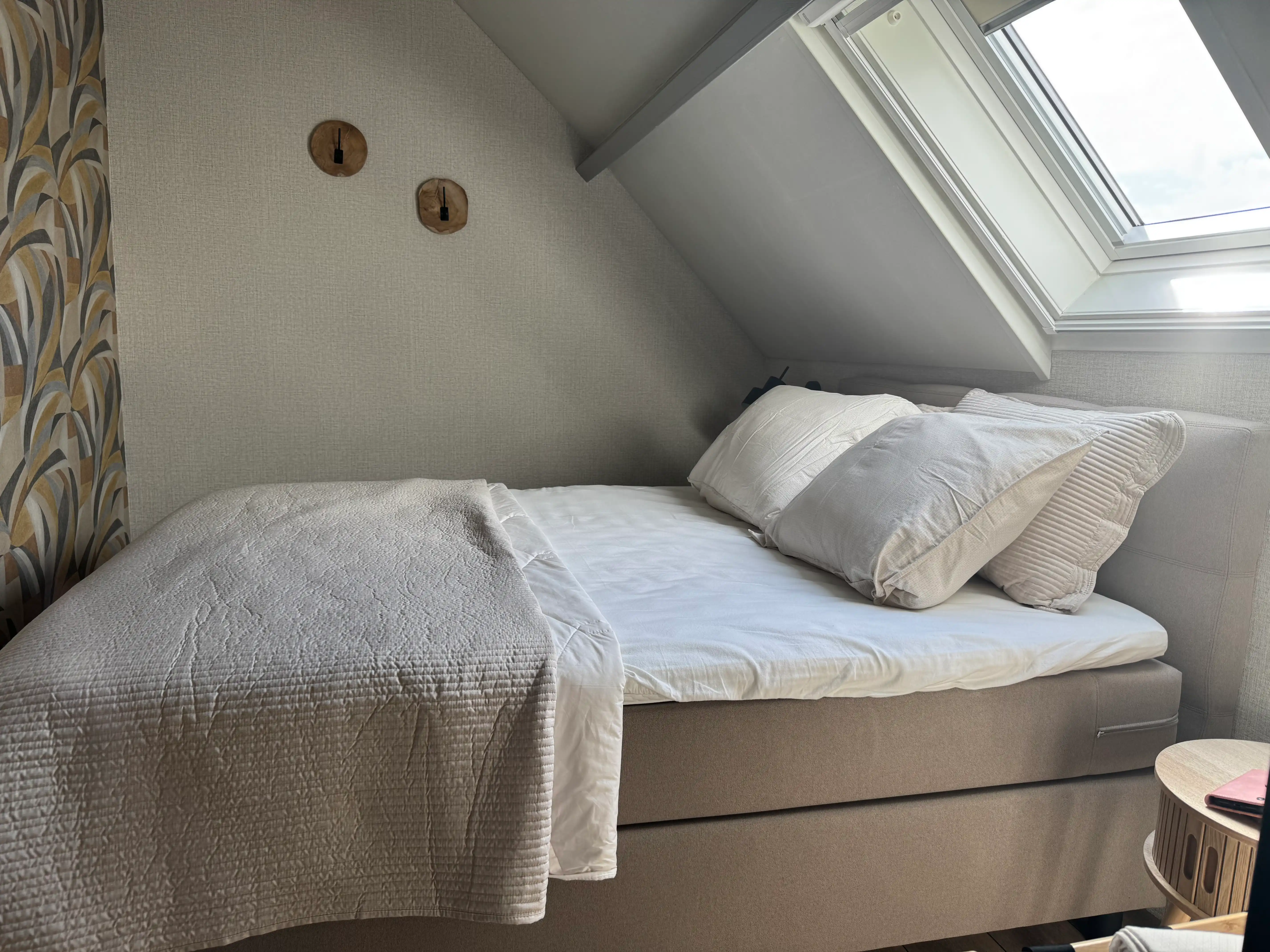 Comfortabel boxspring bed onder een dakraam met natuurlijke lichtinval in Drenthe.