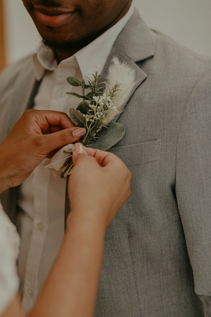 A buttonhole being pinned to a grey suit