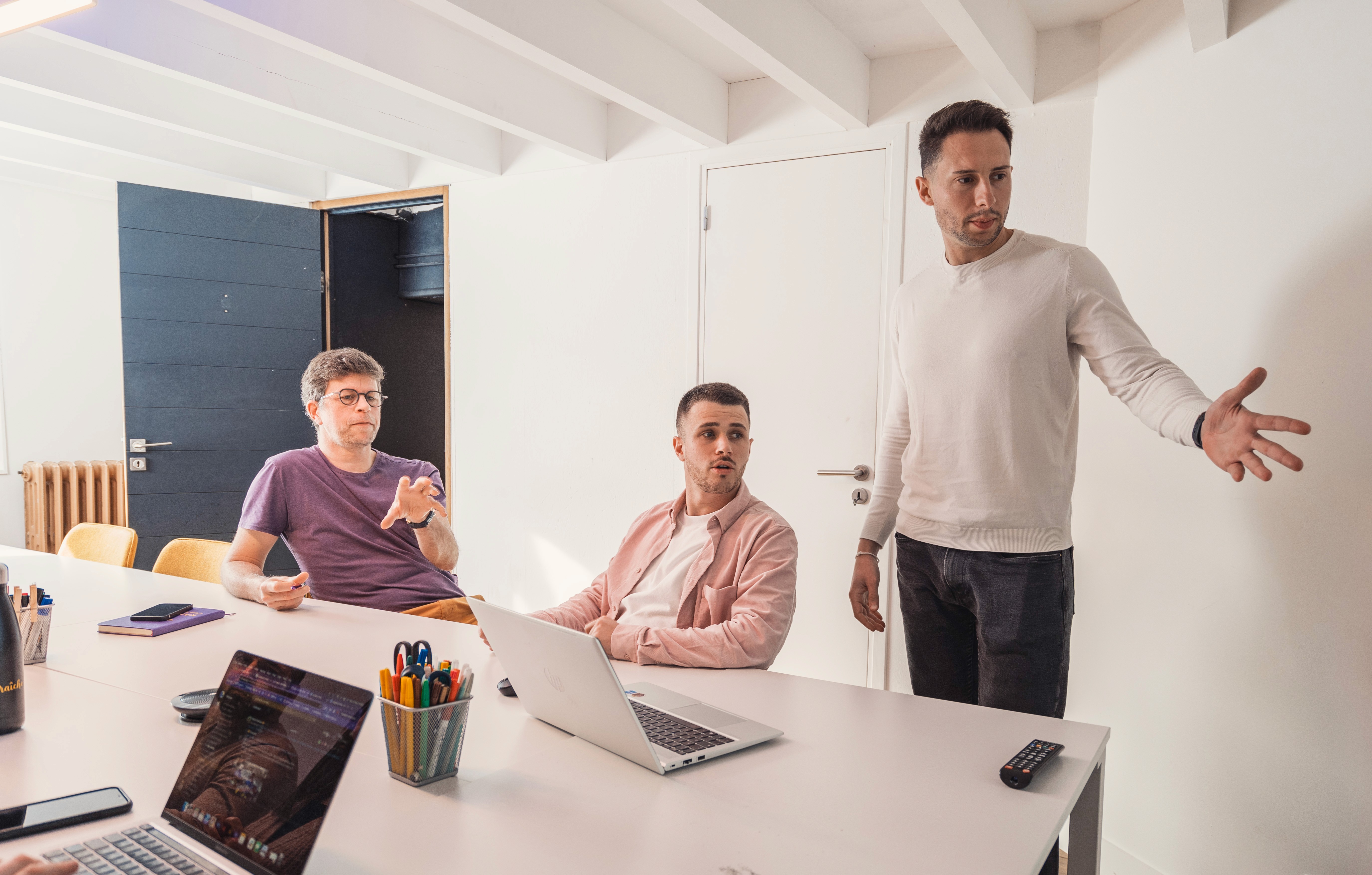 deux personnes installées à un bureau qui parlent et regardent le même écran d'ordinateur