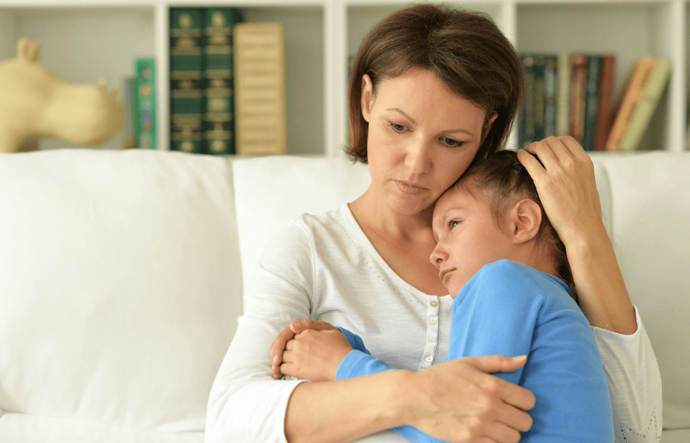 mother holds young daughter on couch