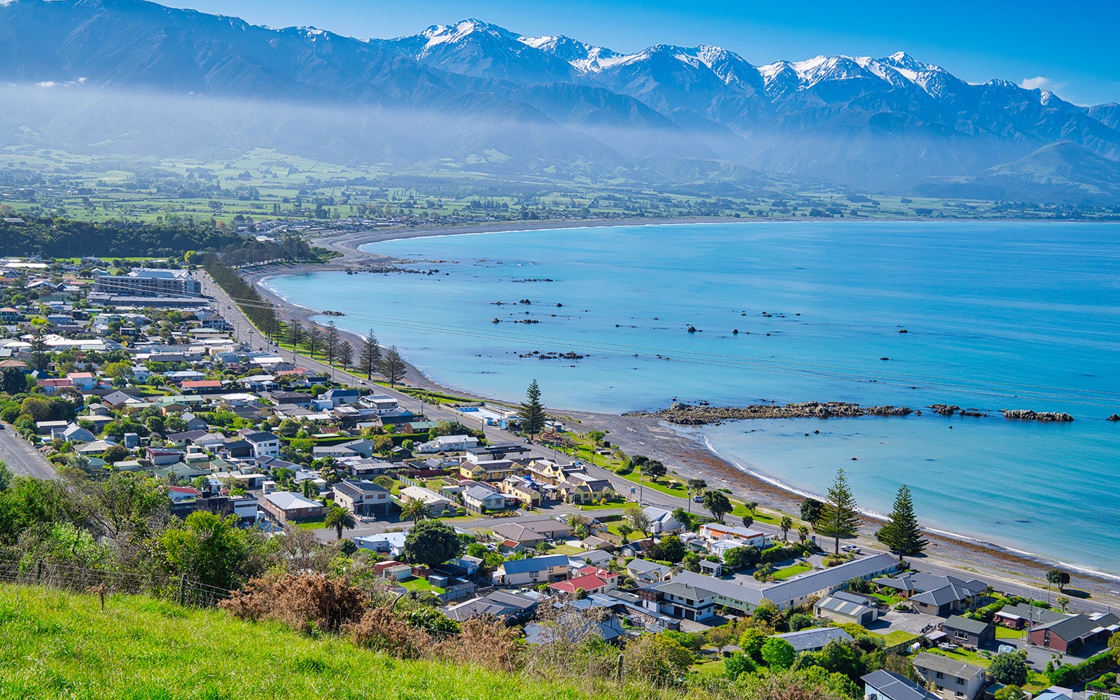 Küstenstadt Kaikoura, Neuseeland, mit Bergen und Ozean im Hintergrund.