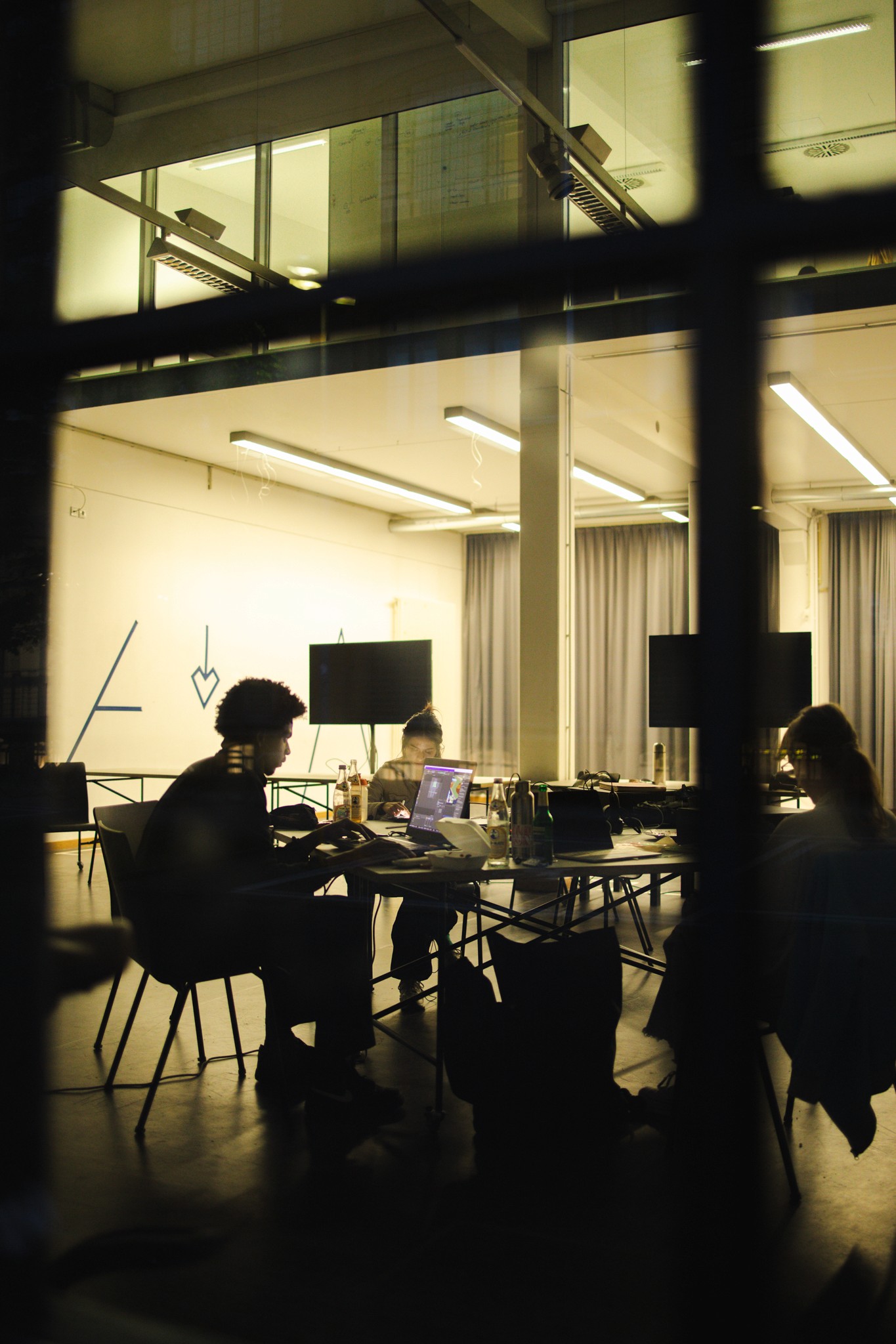 Four diverse professionals collaboratively working on a laptop, with one person pointing at the screen while others observe.