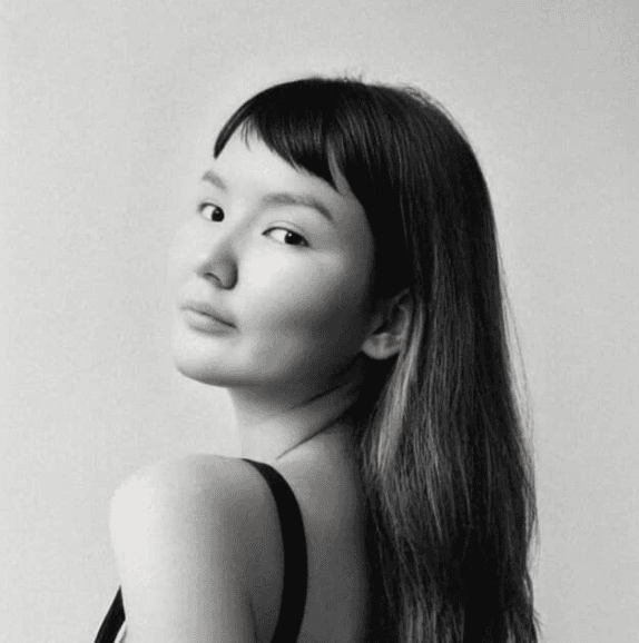 woman in black crew neck t-shirt wearing brown framed eyeglasses standing on rocky shore during