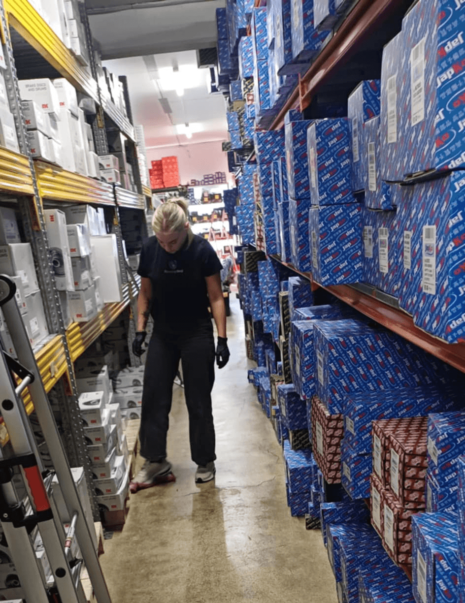 Starfsmaður að þrífa og ganga frá á lager milli hillurekka.
