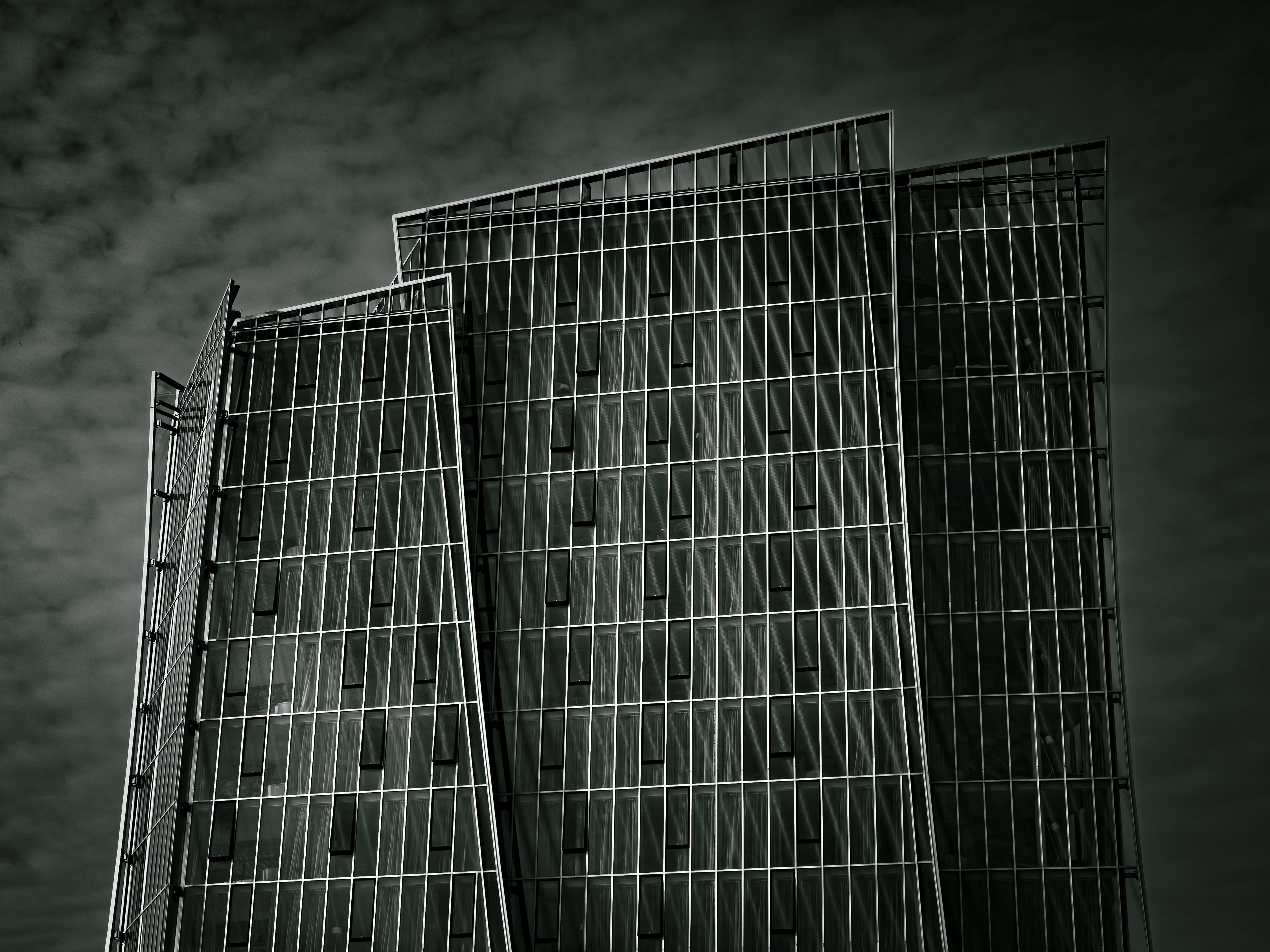 Modern skyscraper with geometric facade against cloudy sky